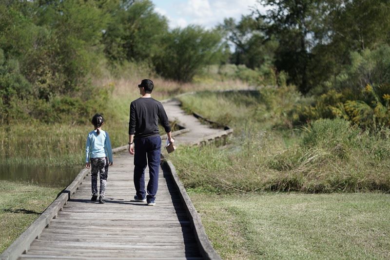 Man and Girl Walking on Boardwalk