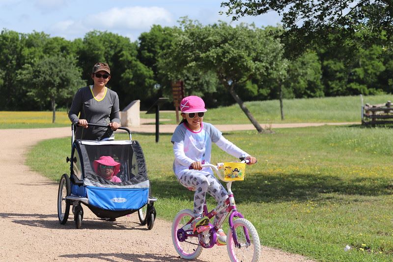 Woman Pushing a Stroller and Girl Biking